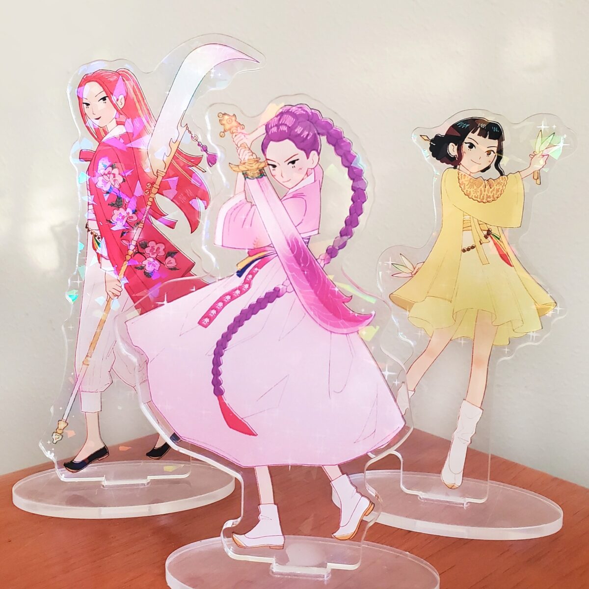 acrylic standees of Rumi, Mira, and Zoey from KPop Demon Hunters dressed in traditional Korean-inspired hanbok clothing