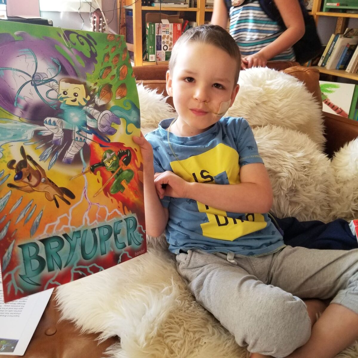 Photo of a child holding a poster of the superhero self they created and was designed by an artist.