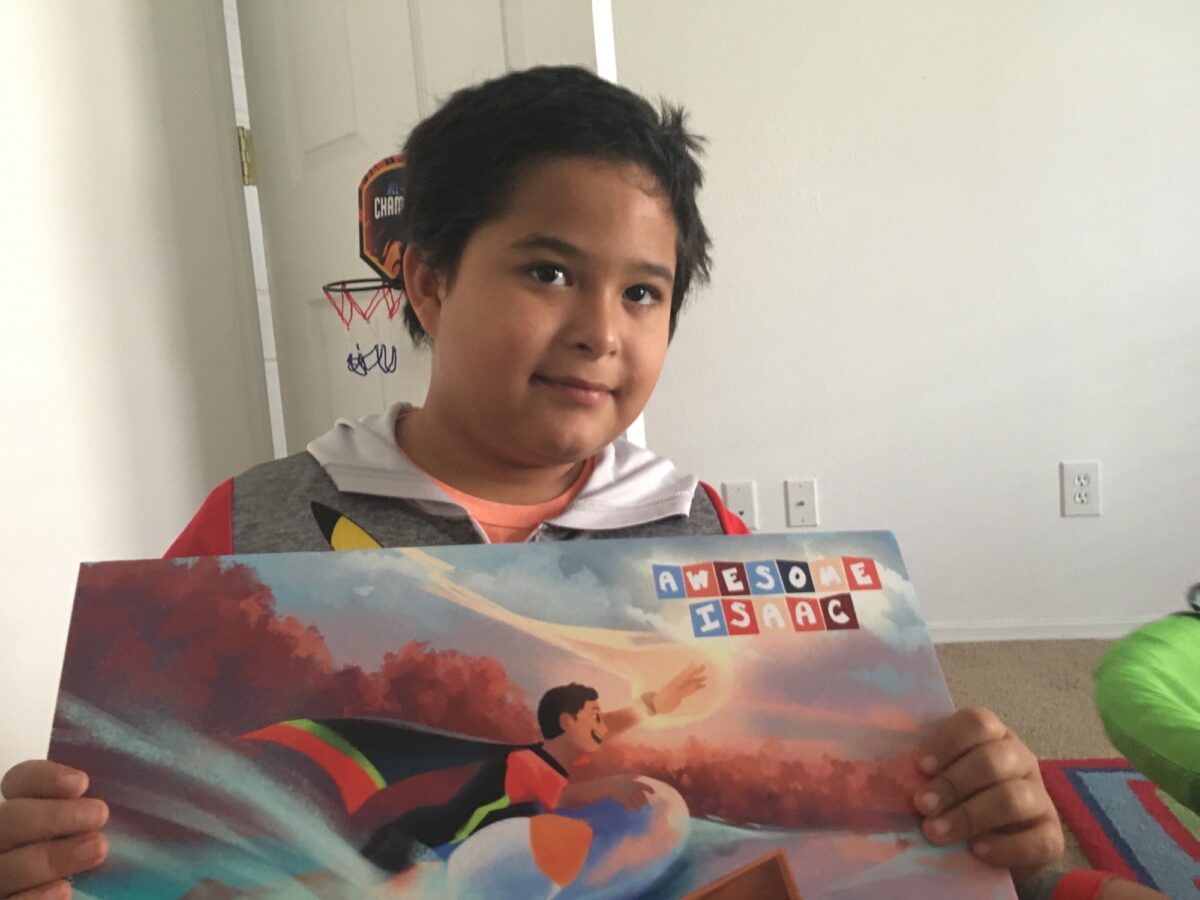 Photo of a child holding a poster of the superhero self they created and was designed by an artist.