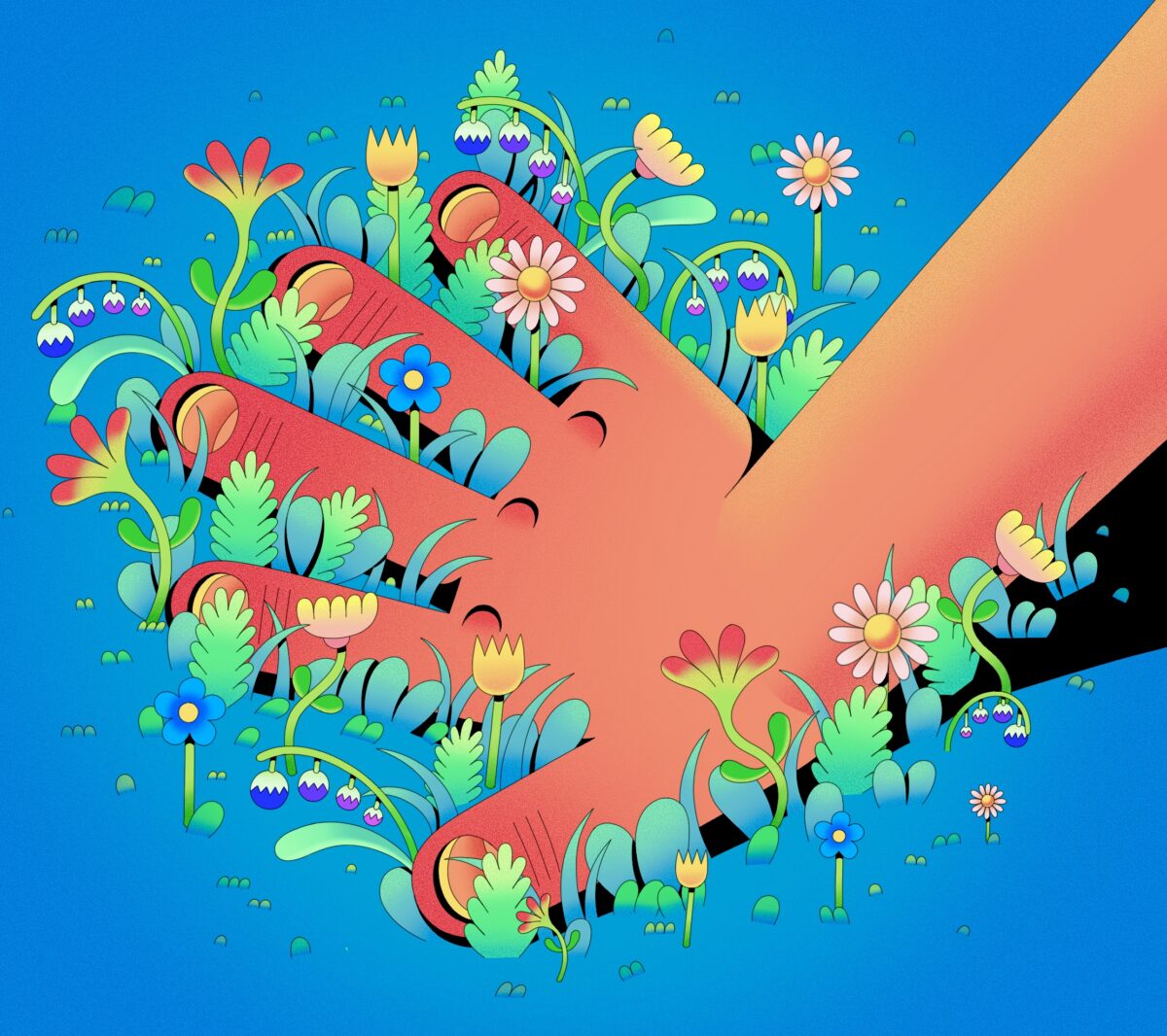Hands touching grass with flowers sprouting out around it